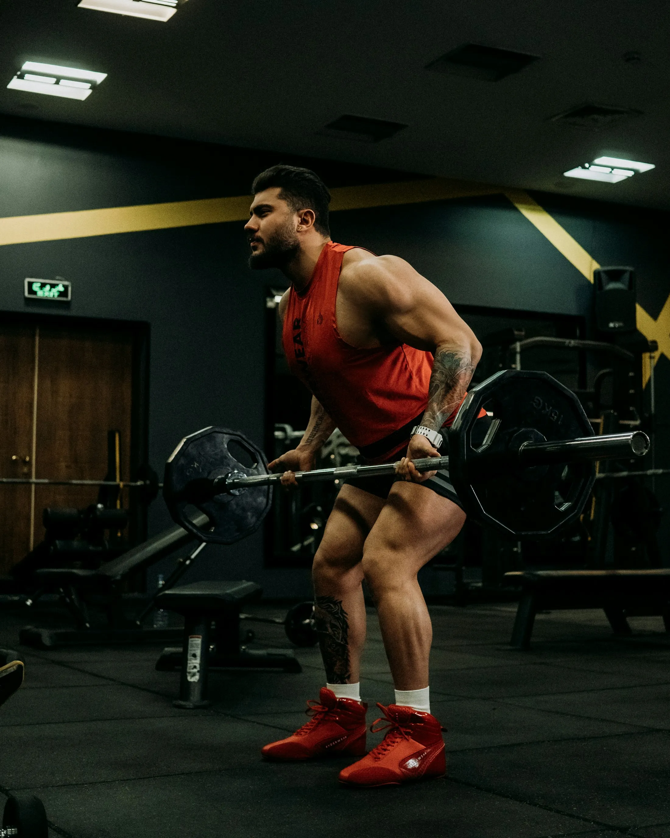 A man squatting with a barbell in a dark gym